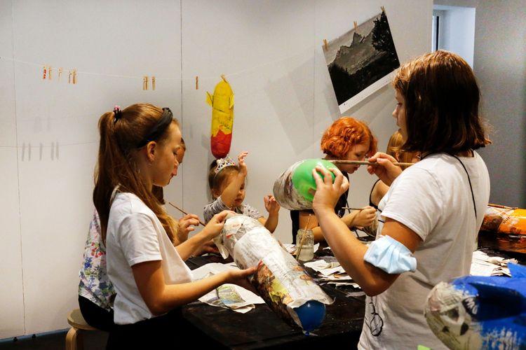 Eine Gruppe von Kindern bastelt mit Ballons und Zeitungspapier.