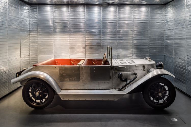 Die Ausstellungsansicht zeigt ein Automobil, das aus Aluminium besteht. Die Innenräume sind mit rotem Leder überzogen. 